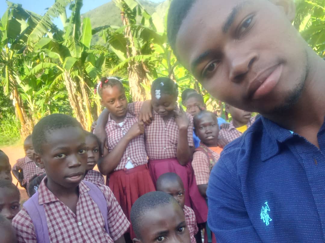 An outreach worker surrounded by children in school uniforms