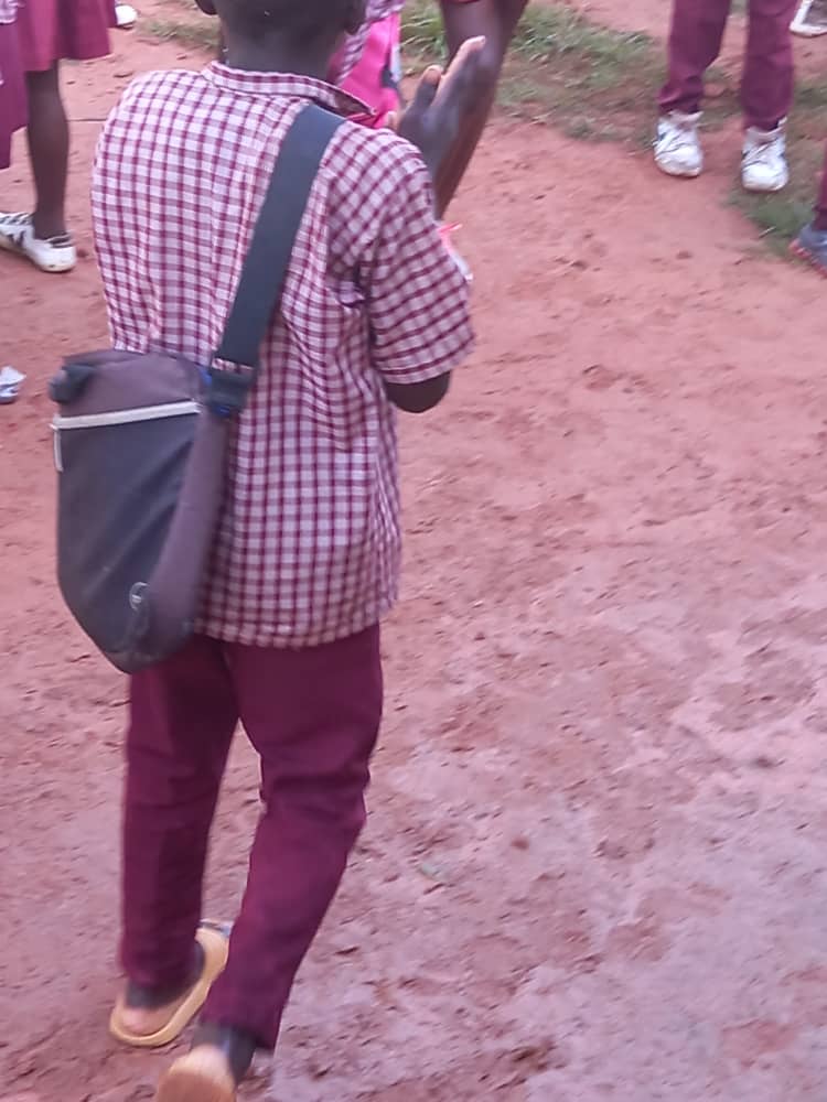 Child seen from behind walking with a small worn bag